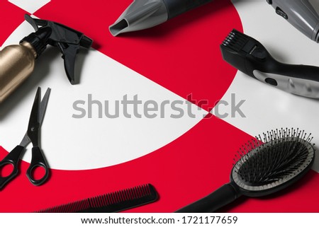 Greenland flag with hair cutting tools. Combs, scissors and hairdressing tools in a beauty salon desktop on a national wooden background.