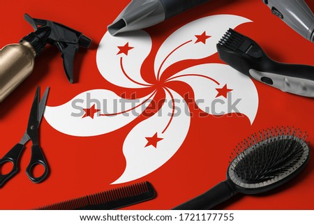 Hong Kong flag with hair cutting tools. Combs, scissors and hairdressing tools in a beauty salon desktop on a national wooden background.