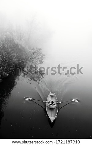 Man in boat in fog. Misty river. Black white photo. Autumn landscape