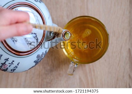 A waiter pours green tea from a teapot into a clear Cup. Hot fragrant green tea. High resolution photos for printing.
