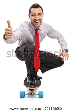 Young businessman kneeling and riding a skateboard and showing thumbs up isolated on white background