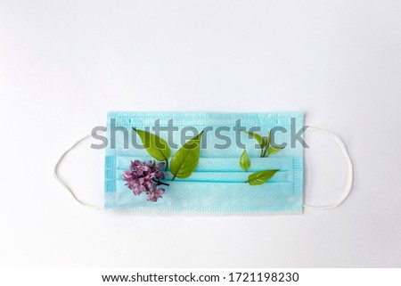 Twigs of flowering plants and a medical mask on a white isolated background. The concept of the arrival of spring and the end of quarantine in connection with the coronavirus pandemic. Flat lay.