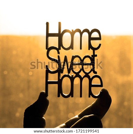 yellow wooden letters with word - HOME SWEET HOME - IN MALE HAND. lettering on sunny window background.