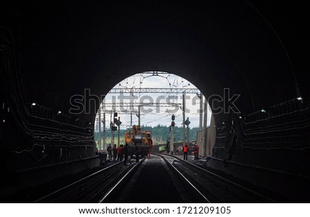 Construction of a new railway tunnel. light at the end of a dark tunnel. portal of a mountain tunnel with workers and machines