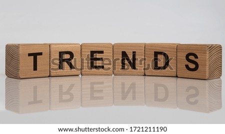 Trends word on wooden cubes with white grey glossy background with reflection