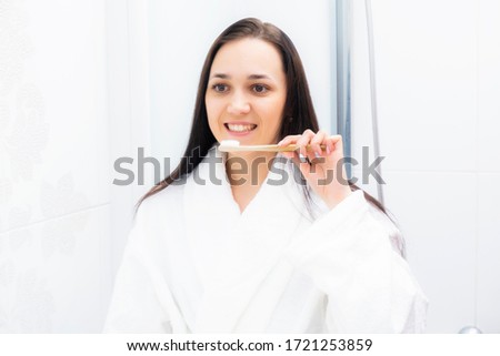 Portrait of brunette in bathroom with bamboo toothbrush for cleaning teeth. Beautiful woman with toothbrush. Oral hygiene.