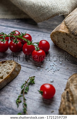 A sliced bread, tomatoes, salt and herbs  on a gray wooden board. Color food photography.
