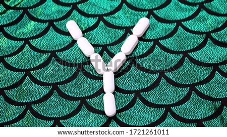 Alphabet made of pills on a green and black background. Vitamins on a background of scales. Abc from drugs. Letter Y made from pills. Capital letter Y of medicines