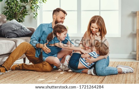 Happy father and mother with little children sitting on floor near sofa and laughing while having fun together at home during weekend
 Royalty-Free Stock Photo #1721264284