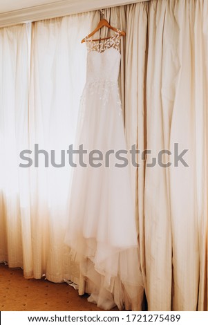 
Wedding lace dress of the bride weighs on a wooden hanger. Cream cream dress. The morning of the bride. Visiting ceremony. Bride and groom. Wedding. 
Сocktail dress, evening dress.