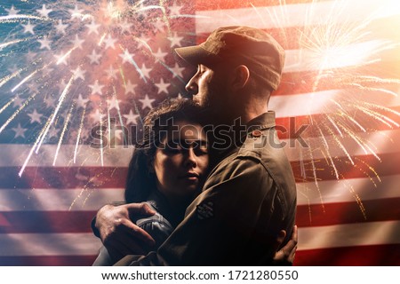 Veterans Day, Memorial Day. A soldier embraces his woman. Couple on the background of the American flag with fireworks. The concept of the American national holidays and patriotism