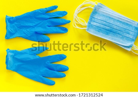 Blue medical gloves and mask on paper yellow background. Coronavirus pandemic.
 Flat lay, top view, copy space concept.
