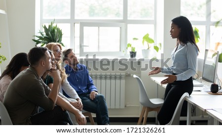Serious african american female leader, mentor holding briefing for team interns in office, teaching students. Confident diverse businesswoman at company meeting with diverse colleagues. Royalty-Free Stock Photo #1721326261