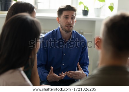 Confident serious male coach mentor talking holding briefing for team employees in office, sharing business strategy. Businessman sitting at company meeting with diverse colleagues. Royalty-Free Stock Photo #1721326285