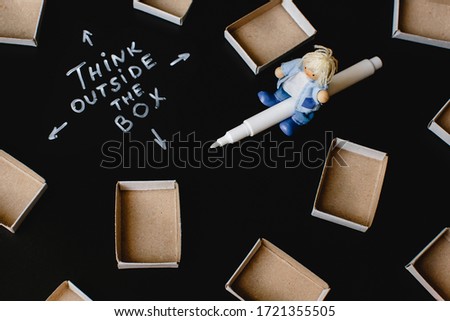 Business concept. Think outside the box. Empty matchboxes, man riding a marker and text on dark background.