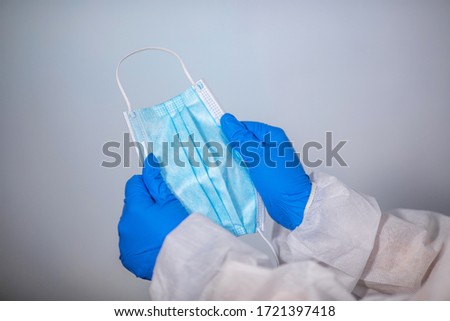 COVID-19. Facial masks on the pile. Epidemic background. Close-up. A medical worker in a protective anti-plague suit holds a maditsin mask with rubber disposable gloves