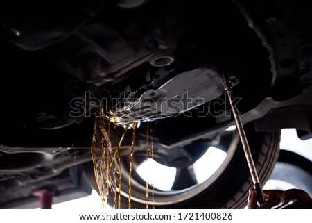 Car mechanic drain the old automatic transmission fluid (ATF) or gear oil at car garage for changing the oil in a gear box of car engine Royalty-Free Stock Photo #1721400826