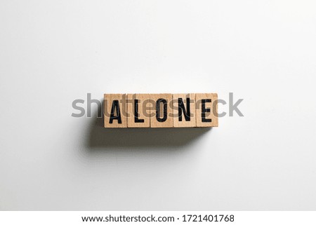 " alone " text made of wooden cube on  White background.