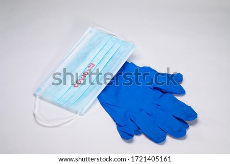COVID-19. Facial masks on the pile. Epidemic background. Sterile disposable medical blue gloves lie next to a medical mask on a white background