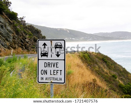 Australian road sign to remind drivers to drive on left side of road. With ocean in the background.