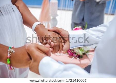 Bride and groom exchanging wedding rings close up during symbolic nautical decor destination wedding marriage on sandy beach in front of the ocean in Punta Cana, Dominican republic  