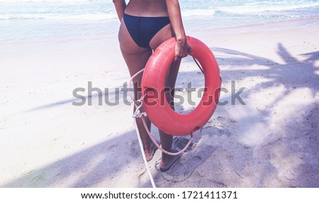 The young women with the lifebuoy on the shore. Lifebuoy on the beach near the water. Save life . Samui Thailand.