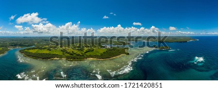 Panoramic view of Salvacion's beach in siargao island, philippines, the sea on the righ side, waves, and the sky in the background 