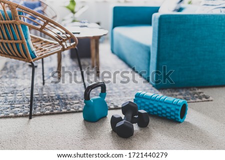 home gym and exercising indoor concept, set of fitness gear on living room carpet next to the couch in a living room shot at shallow depth of field Royalty-Free Stock Photo #1721440279