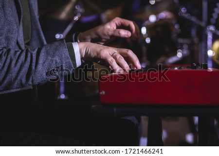 Concert view of a musical keyboard piano player during musical jazz band orchestra performing, keyboardist hands during concert, male pianist on stage
