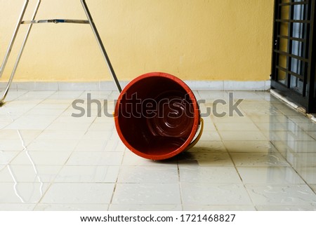 A picture of empty plastic bucket on wet floor during floor cleaning.