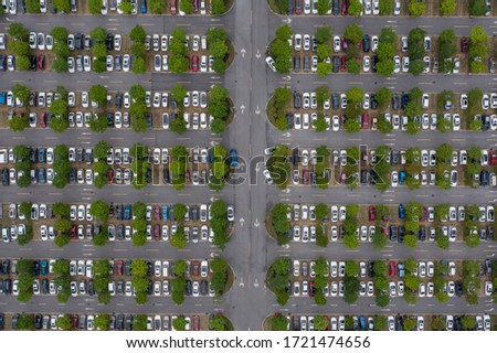 Top view of many cars parked in outdoor parking lot full of trees