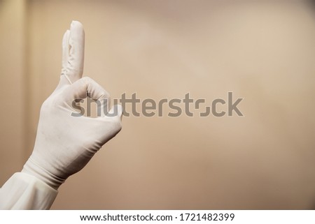 hand wearing medical glove and show symbol o.k. on background.