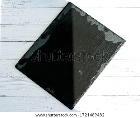 shadowed slate dish on white wooden background.