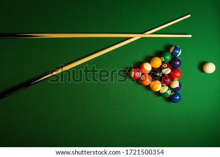 backdrop of pyramid of pool balls and billiard cues on green billiard table Royalty-Free Stock Photo #1721500354