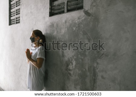 Portrait of woman in gray medical mask close-up. Covid-19 Virus Prevention. 
The doctor prays for recovery. Hands in namaste.