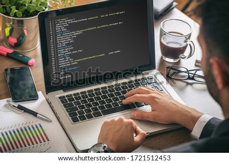 Man programmer making a code on a computer screen, office, business background. Software, programming concept