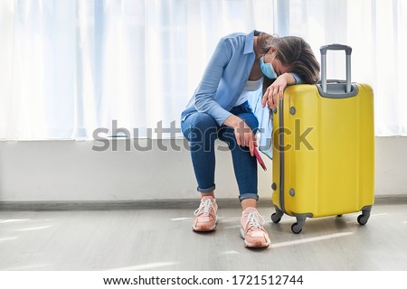 Woman traveler in face protective mask affected by flight delay and cancelled travel and vacation. Travel ban due to coronavirus outbreak and covid-19 ncov virus epidemic                  Royalty-Free Stock Photo #1721512744