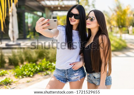 Lifestyle selfie portrait of two young positive woman having fun and making selfie
