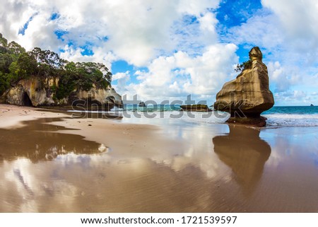  Cathedral Cave on the North Island. Bizarre clouds and coastal cliffs reflected in the tidal waters of the Pacific Ocean. Coromandel Peninsula. The concept of exotic, ecological and photo tourism