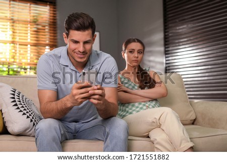 Man preferring smartphone over spending time with his girlfriend at home. Jealousy in relationship Royalty-Free Stock Photo #1721551882