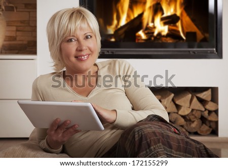 Pretty adult female using digital tablet computer, looking at camera 