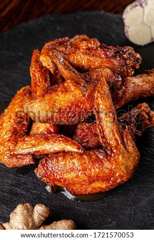 American cuisine. Fried chicken wings glazed in marinated with ginger and garlic on a black background. background image, copy space text.