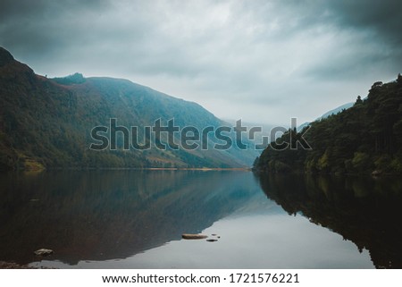Glendalough Upper Lake in Ireland. Dark and moody irish Landscape with cloudy mouintains and forest. Mountain Lake.