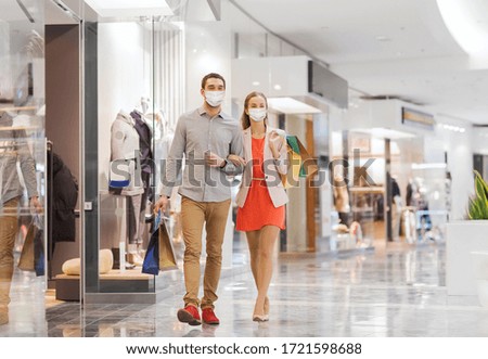 sale, consumerism and pandemic concept - happy young couple wearing face protective medical mask for protection from virus disease with shopping bags walking in mall Royalty-Free Stock Photo #1721598688