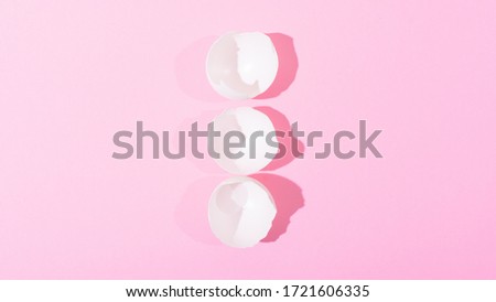White eggshell on a pink background, view from above.