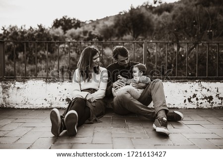 Lovely couple sitting on the floor with their baby at home terrace.