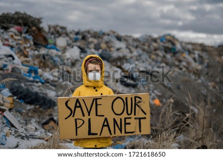 Small child holding placard poster on landfill, environmental pollution concept. Royalty-Free Stock Photo #1721618650