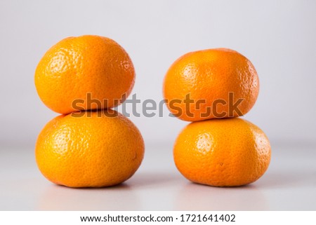 2 turrets of 4 ripe tangerines on a light gray background