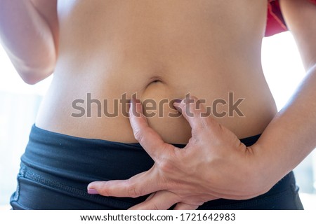 Young woman holding with her fingers her belly button to create a sad mouth Royalty-Free Stock Photo #1721642983