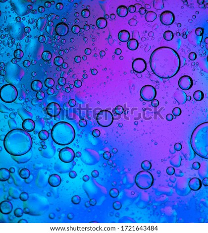 A surface with blue to purple gradient with a lot of water drops on it.